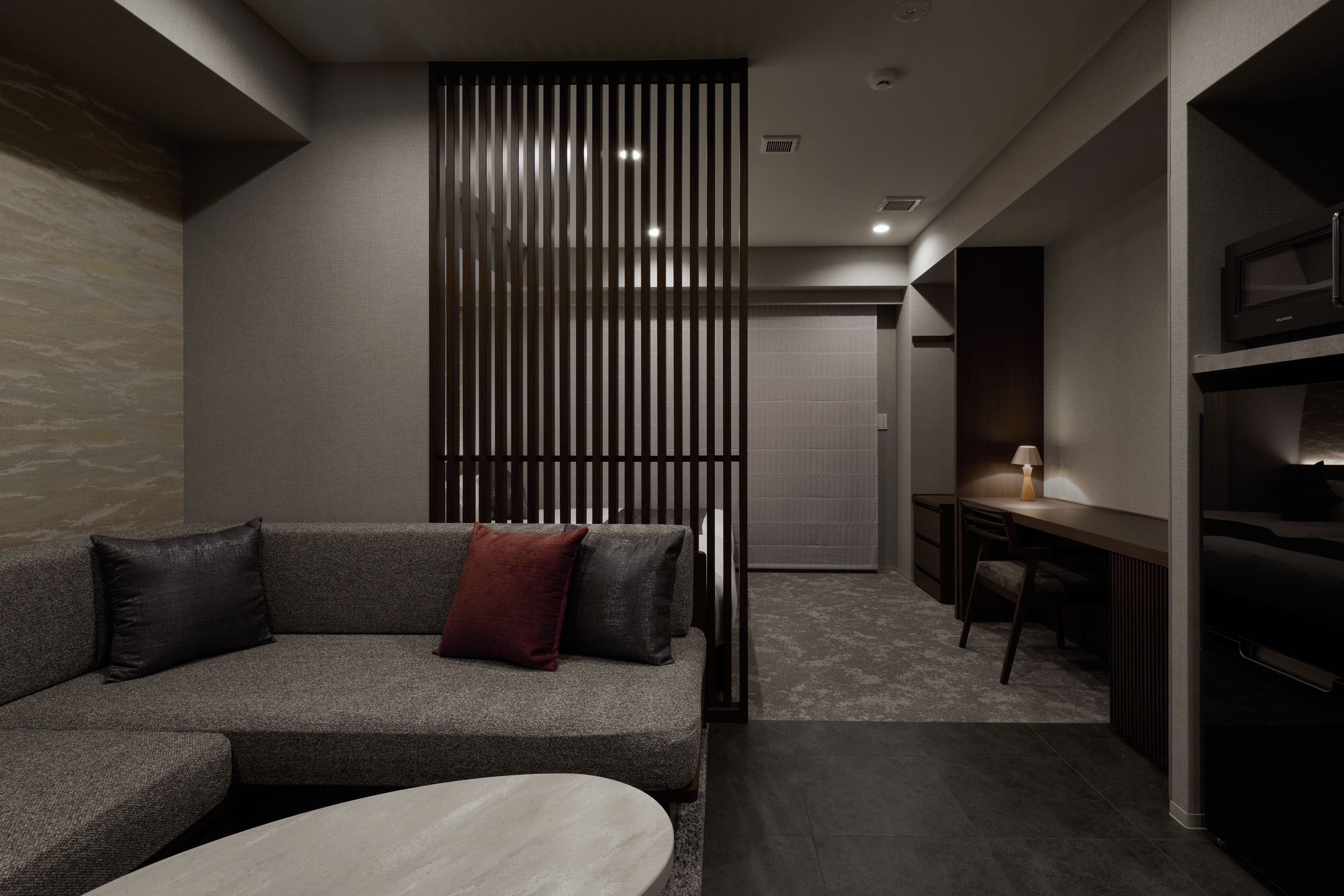 A modern living room with a sofa, a coffee table, and a desk area.