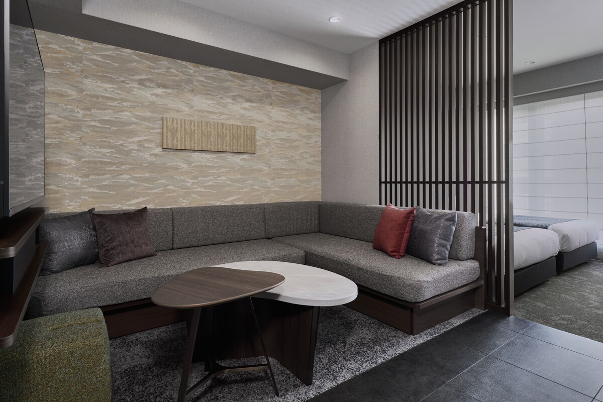 A modern living room with a sectional sofa, a small round table, and a decorative wall piece.