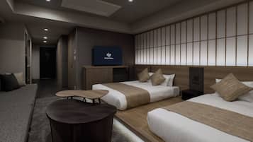 Una habitación de hotel moderna con un sofá, dos camas, una mesita y un televisor mostrando 'GRAND MONDAY'.