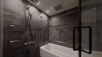 A modern bathroom with a glass-enclosed shower, a white bathtub, and a handheld showerhead.