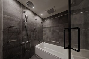 A modern bathroom with a glass-enclosed shower, a white bathtub, and a handheld showerhead. - GRAND MONday KYOTO SHIJO KAWARAMACHI (Kyoto)