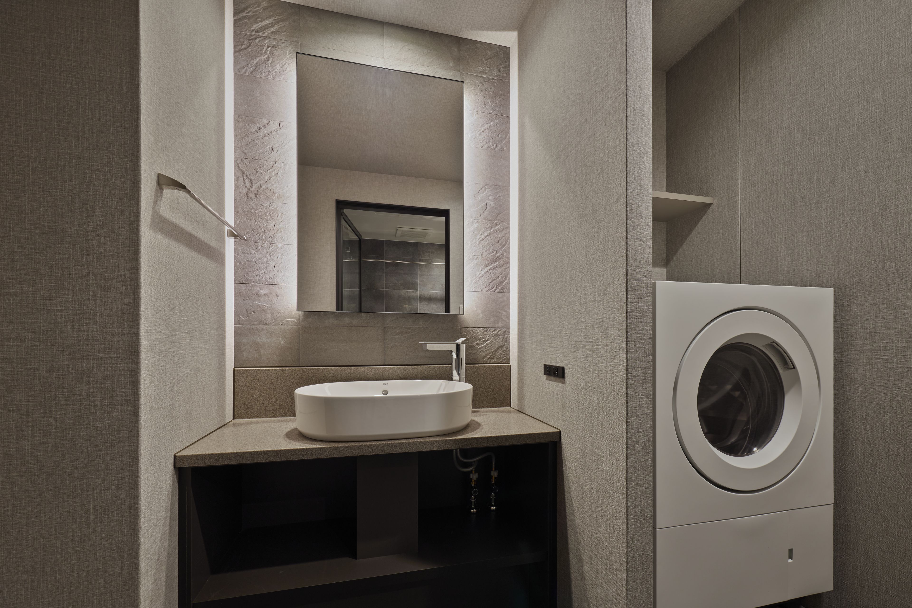 Une salle de bain moderne avec un lavabo intégré, un miroir et un lave-linge à chargement frontal.