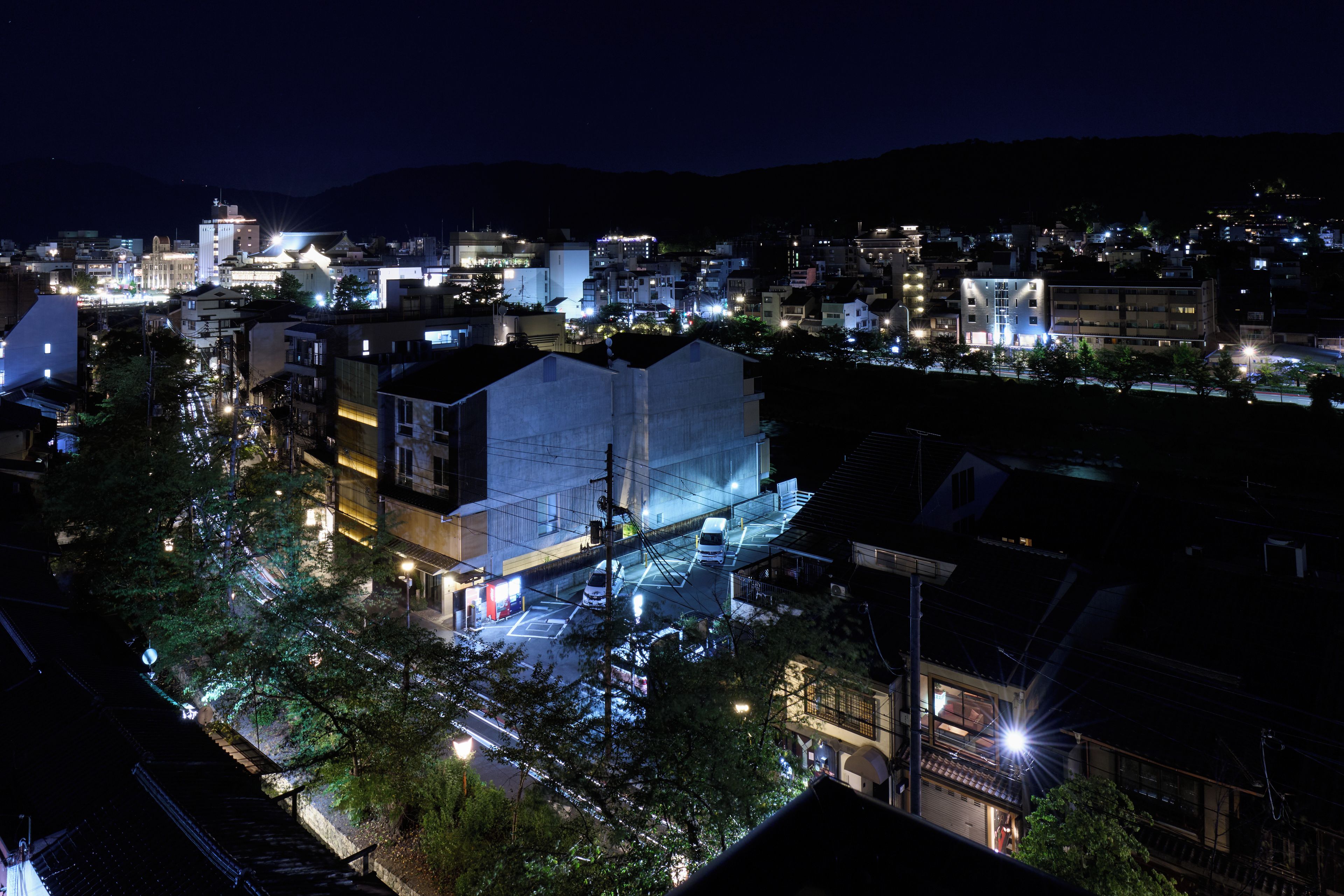 Une vue nocturne d’une ville, avec ses bâtiments illuminés et un parking.