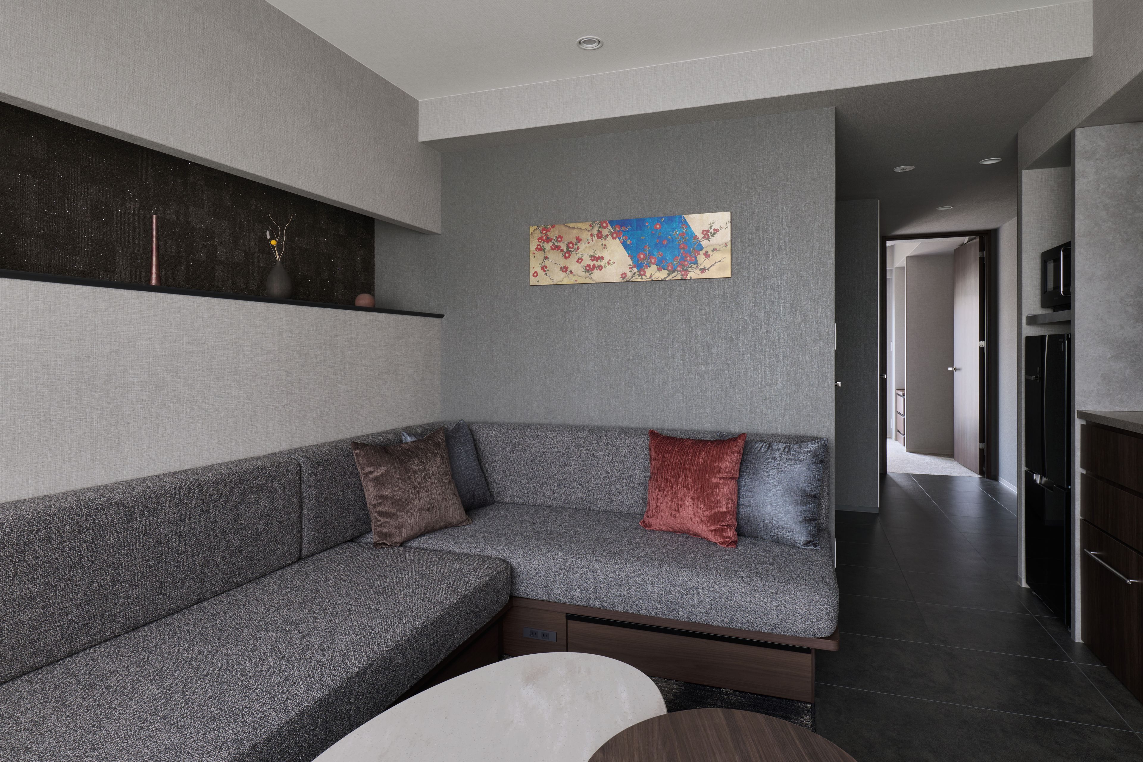Un saló modern amb un sofà seccional gris, un televisor de pantalla plana fixat a la paret, i un estil decoratiu minimalista.