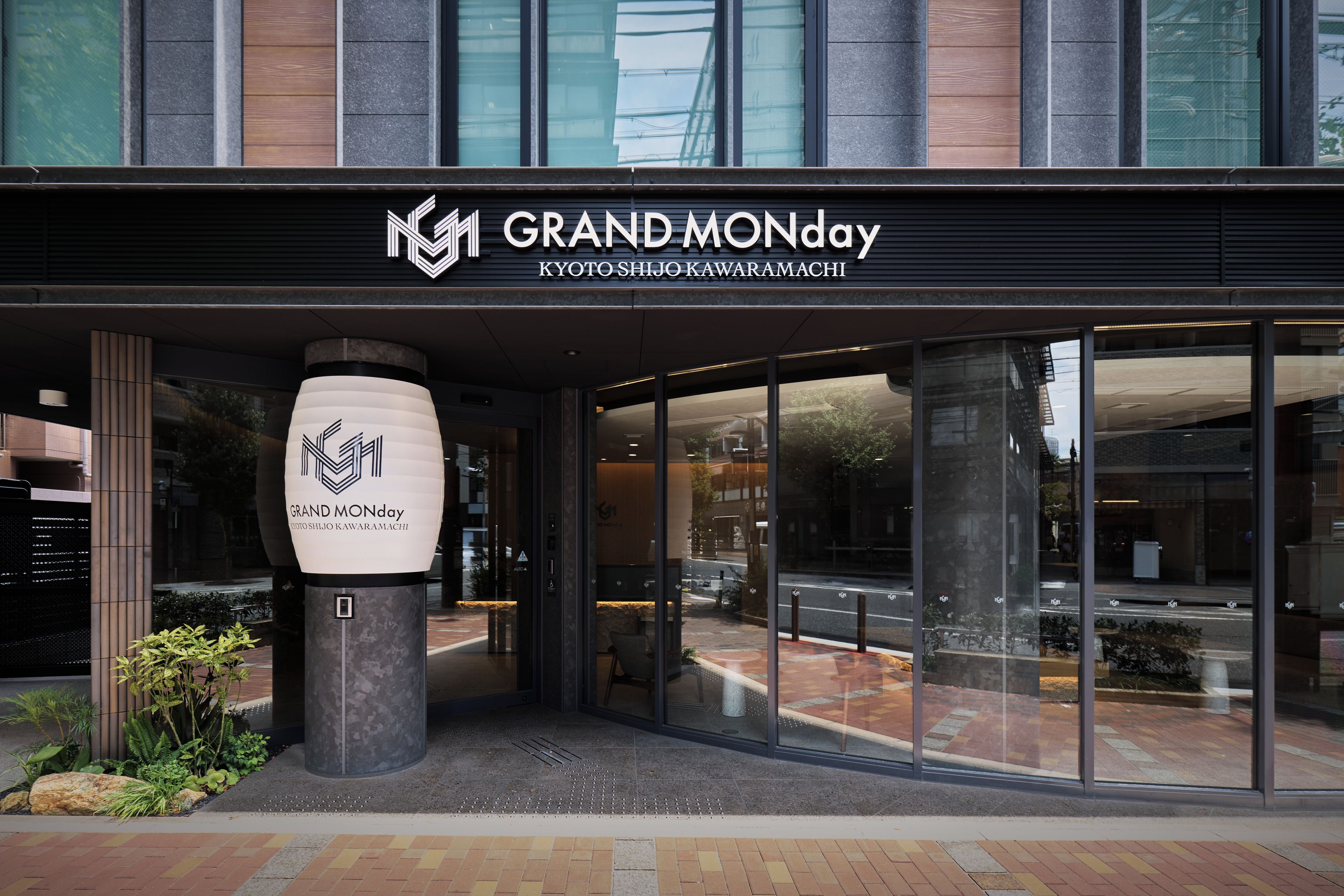 The exterior of a hotel with a modern facade, large glass windows, and a prominent logo.