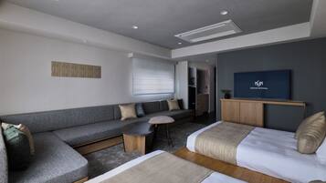 A modern hotel room with a sofa, a bed, a small table, and a television.