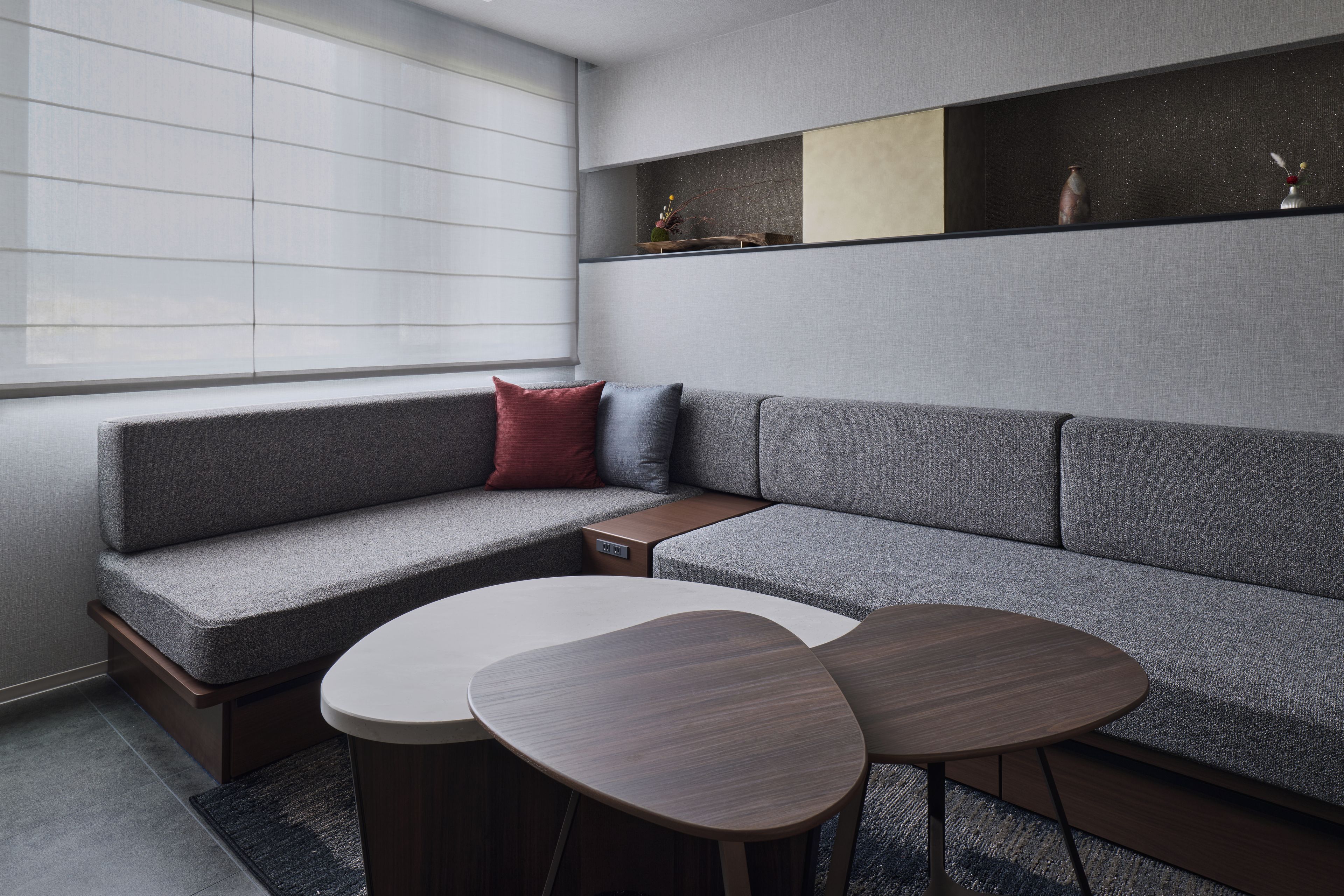 A modern living room with a grey sectional sofa, a small wooden side table, and two round coffee tables.
