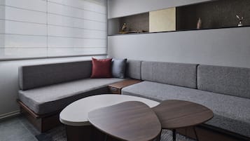 A modern living room with a grey sectional sofa, a small wooden side table, and two round coffee tables.
