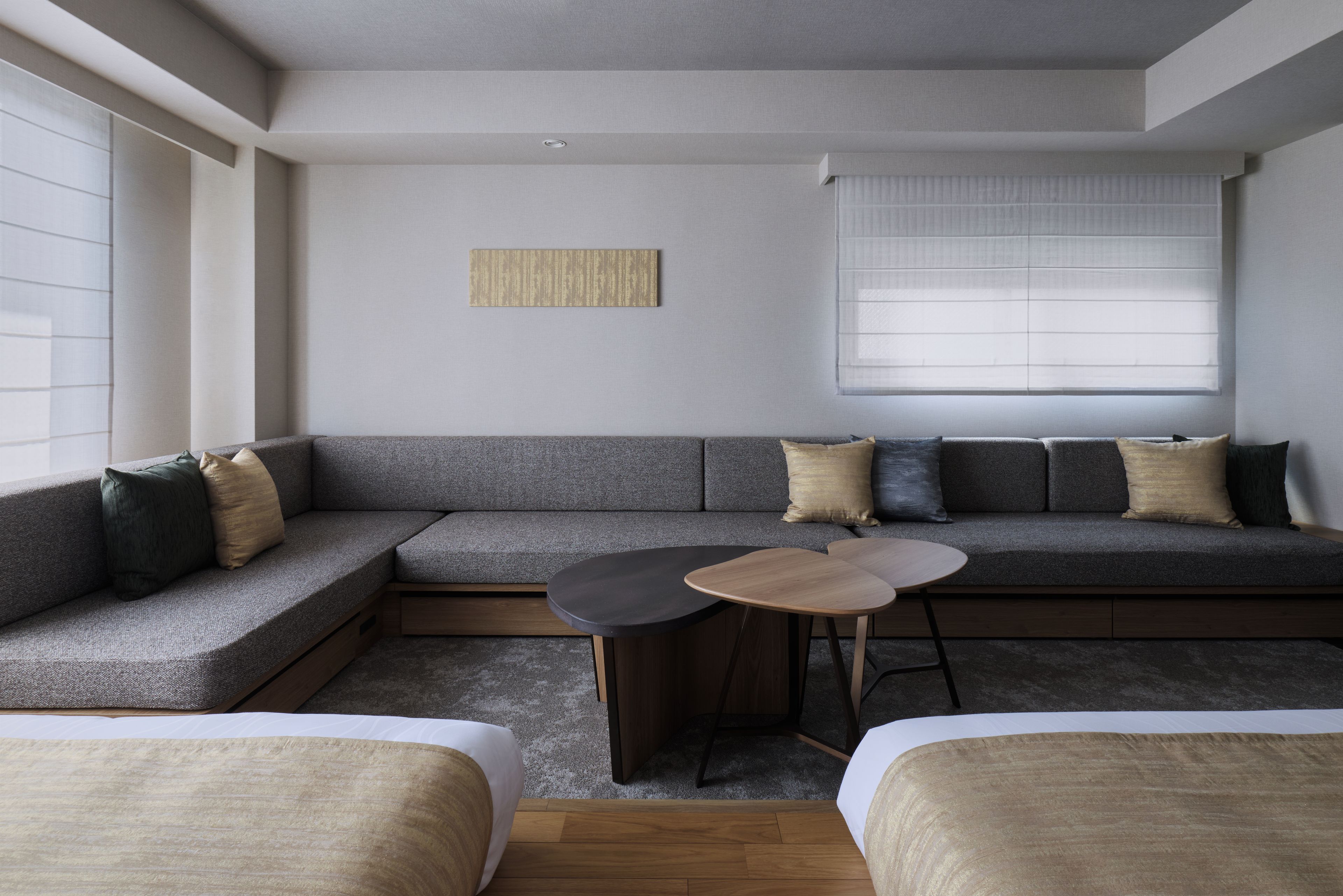 A modern, minimalist room with a sectional sofa, a small round table, and a window with blinds.