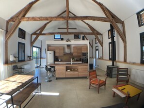 Une cuisine spacieuse avec des poutres apparentes en bois, un îlot central et des appareils électroménagers modernes.