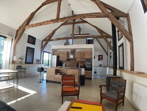 A spacious interior with exposed wooden beams, a central island with seating, and a kitchen area with modern appliances. - Vacation rental with a pool for 6 people in the heart of the Périgord Noir (Veyrines-de-Domme)