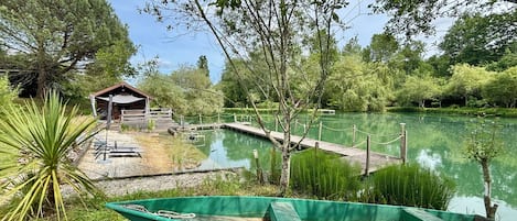 A serene lakeside setting with a wooden dock, a small pavilion, and a green boat.