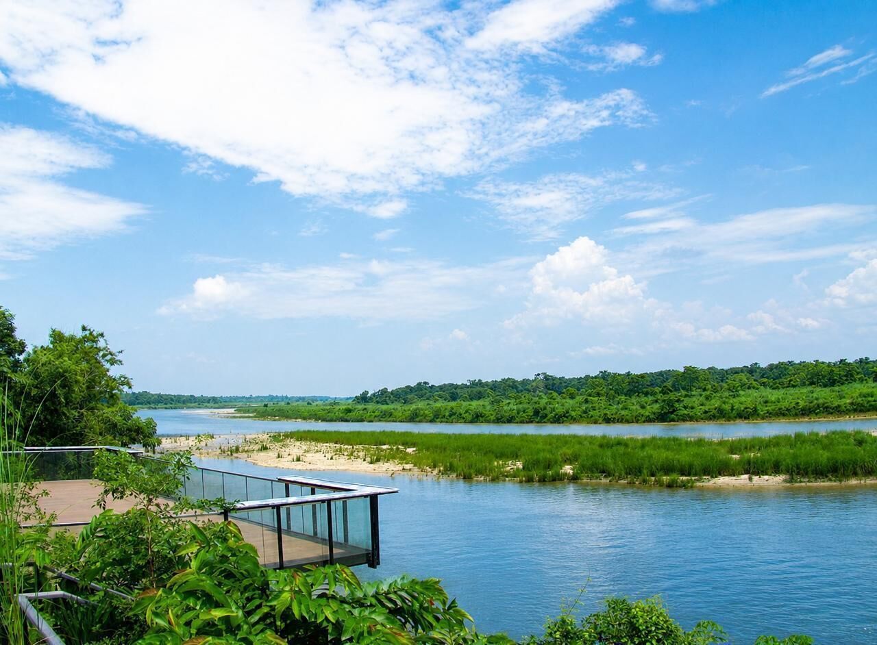 Vista al río con una terraza de madera y barandilla de vidrio, con vistas a un río tranquilo.