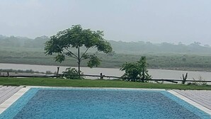 A swimming pool with a view of a lake and trees in the background.