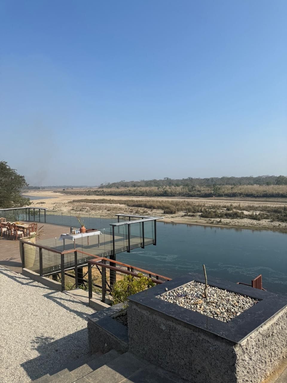 Eine Terrassenförmige Sitzgelegenheit am Flussufer mit Außenbestuhlung und Feuerstelle.