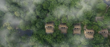 An aerial view of a residential area with multiple houses surrounded by dense forest.