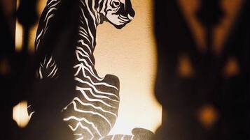 Silueta de un tigre frente a una pared, enmarcada por una ventana con vista a un suelo de baldosas.