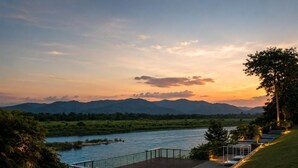 A riverside deck with a view of a river and mountains in the distance.