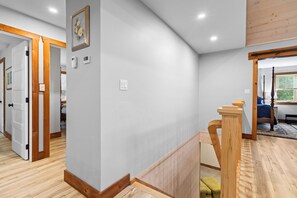 Ein modernes Interieur mit einer Holztreppe, einem gerahmten Bild an der Wand und einem Bett mit Blick aus dem Fenster.