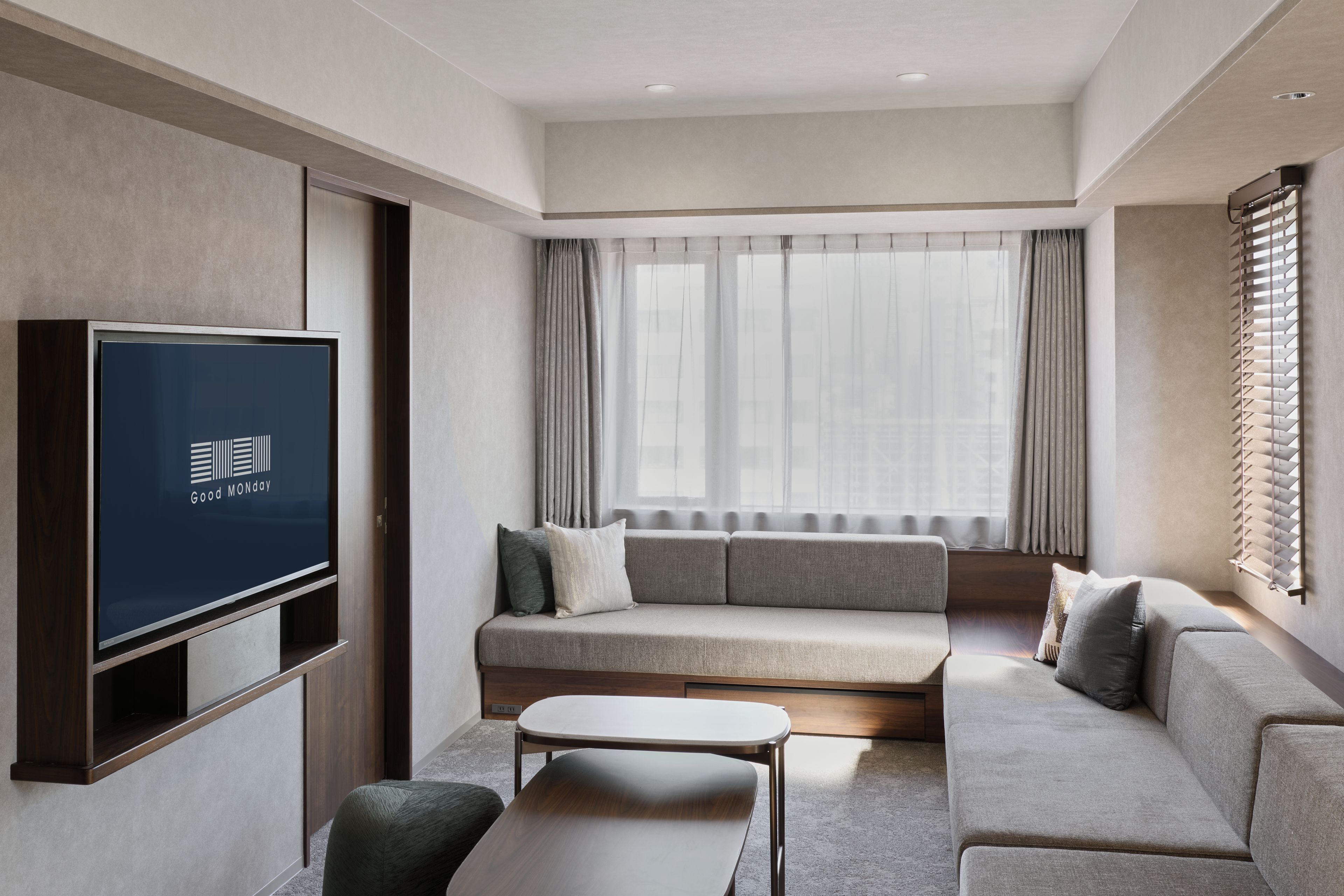 A modern living room with a flat-screen TV, a sofa, a coffee table, and a window with curtains.