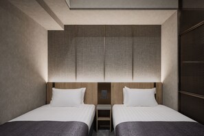 A hotel room with two beds, a wooden headboard, a small bedside table, and a wall-mounted control panel. - Good MONday ASAKUSA (Tokyo)