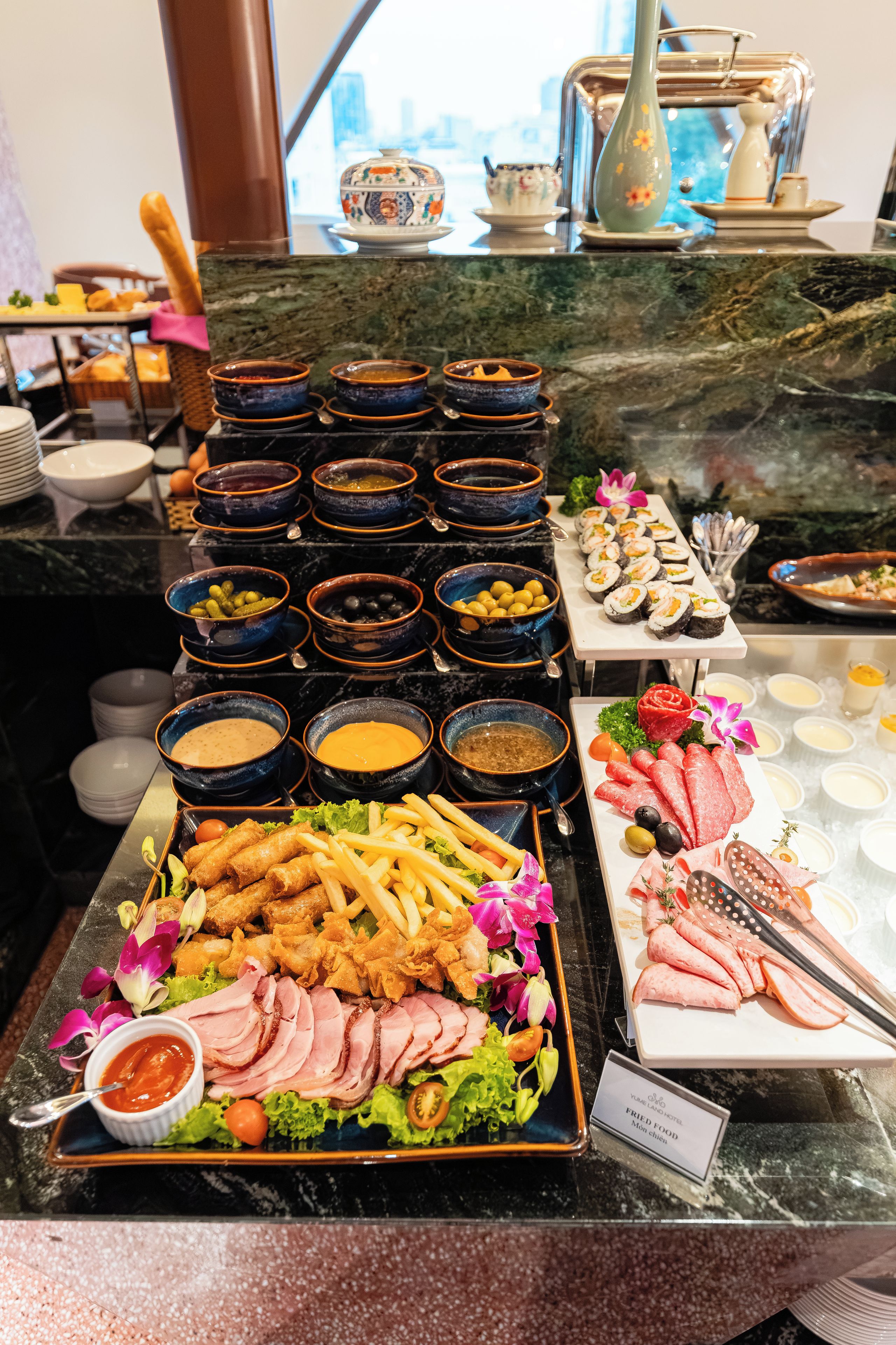Un bufé con diversos alimentos, incluyendo sushi, carnes y salsas.
