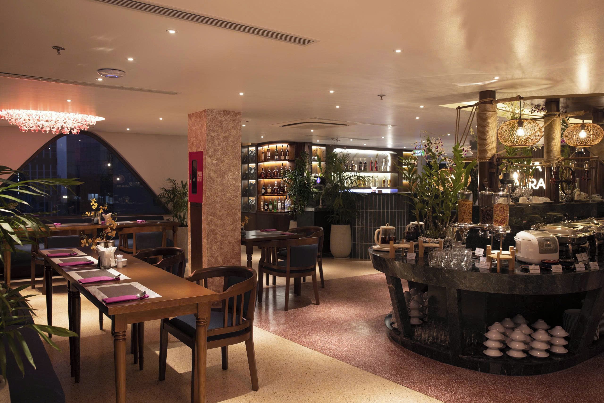 A restaurant with a bar area, seating arrangements, and a variety of bottles on shelves.