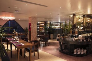 A restaurant with a bar area, seating arrangements, and a variety of bottles on shelves. - Yume Land Hotel (Ho Chi Minh City)