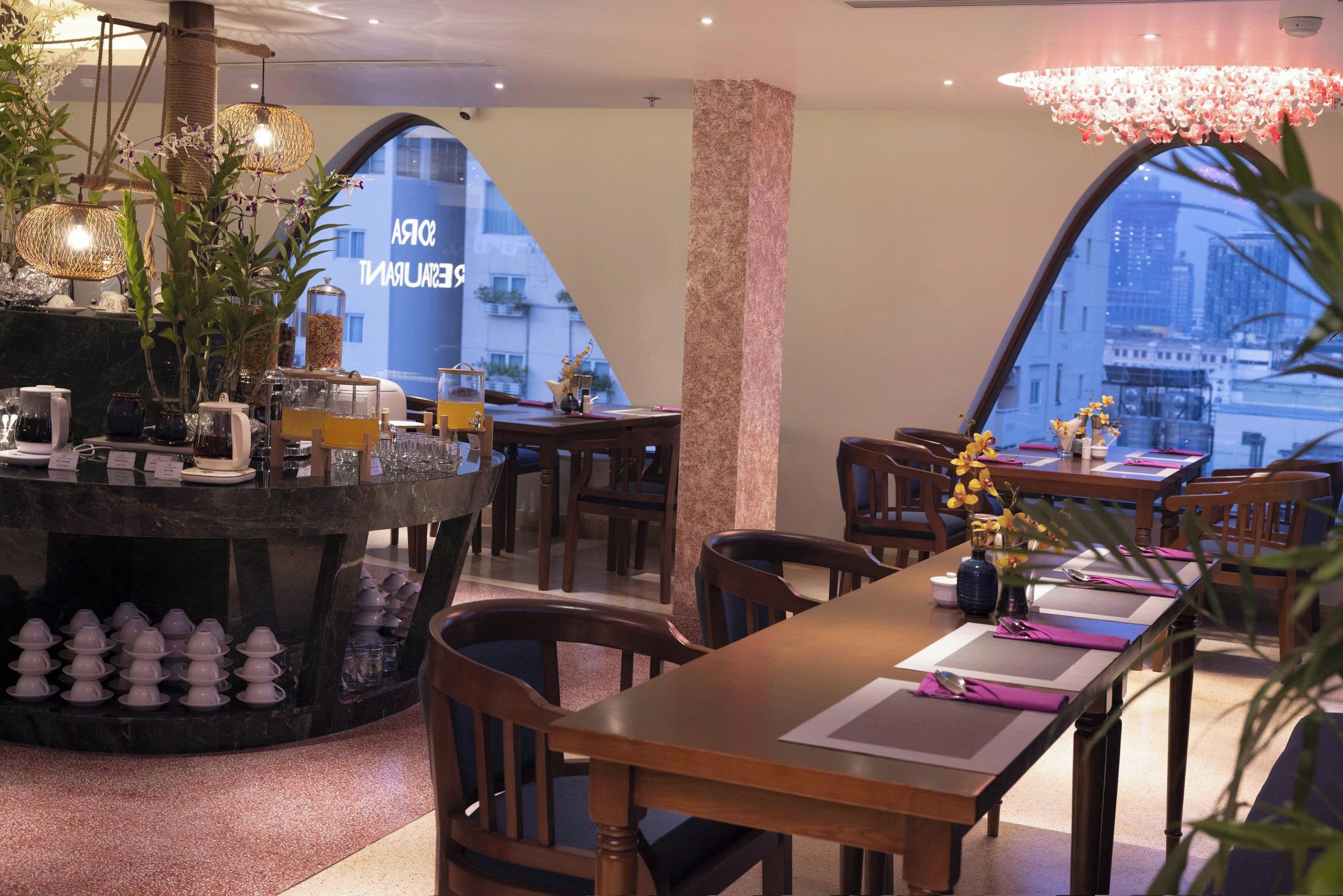 Un restaurante con zona de bar, mesas, sillas y vistas panorámicas de la ciudad a través de amplios ventanales.