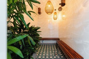 A hallway with a bench, a patterned floor, and hanging lamps.