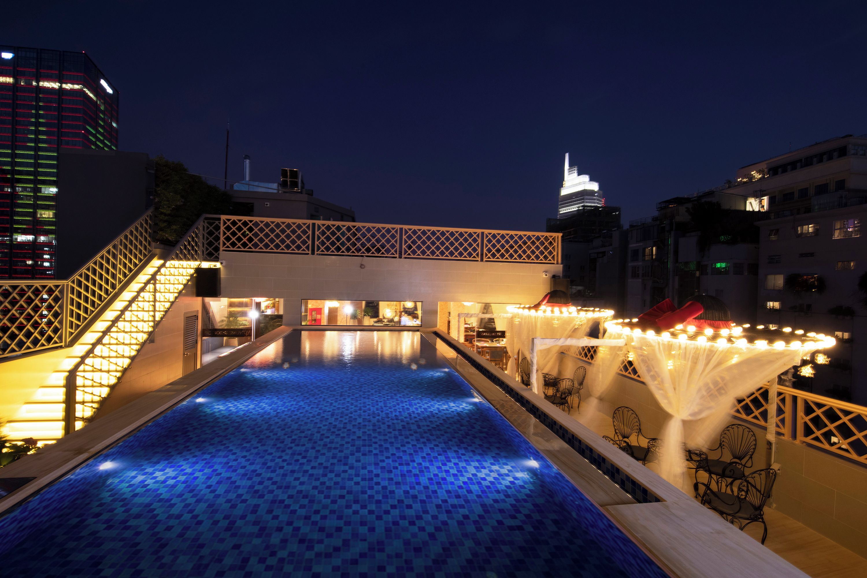 Una piscina en la azotea con vistas a un horizonte urbano nocturno.