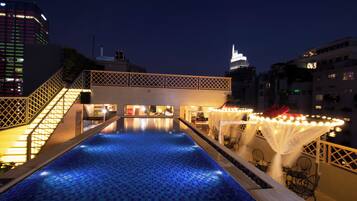Una piscina en la azotea con vistas a un horizonte urbano nocturno.