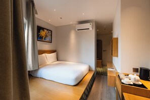A hotel room with a bed, a painting, an air conditioning unit, and a small kitchenette area. - Yume Land Hotel (Ho Chi Minh City)