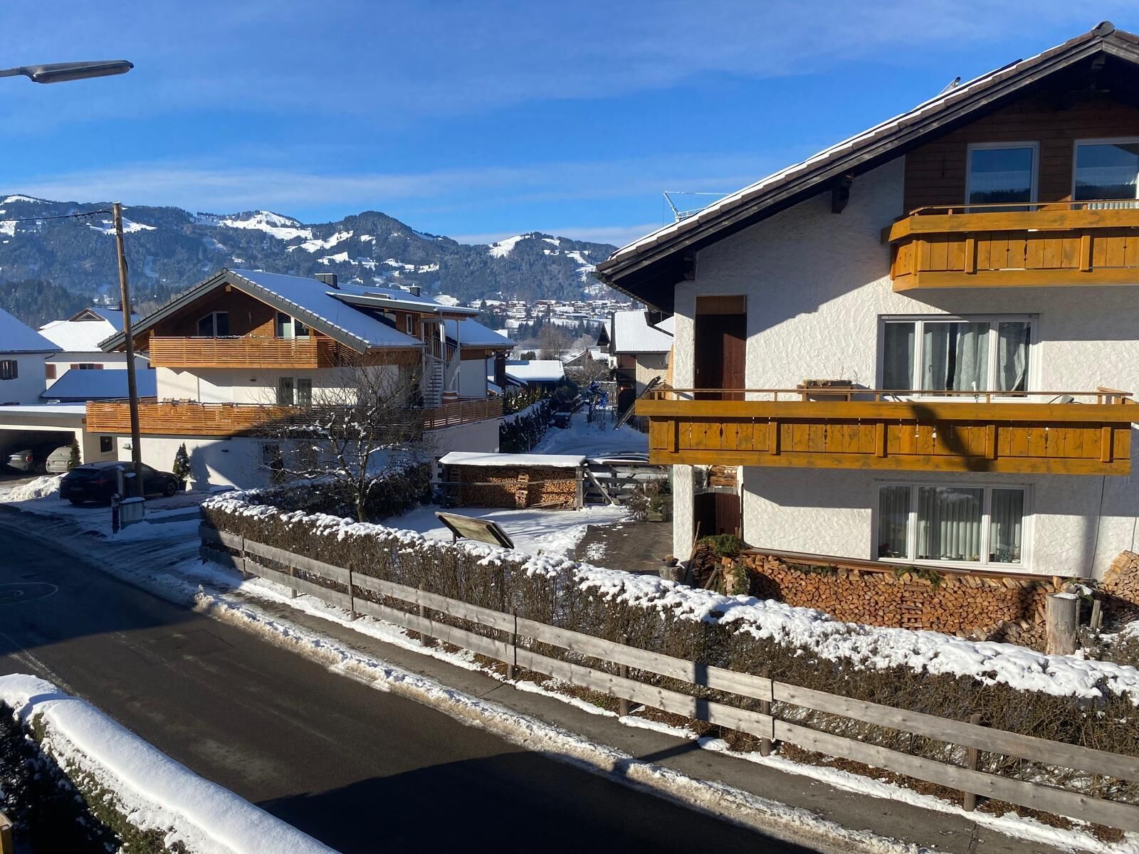 Ein Wohngebiet mit Häusern, einer Straße und verschneiten Bergen im Hintergrund.