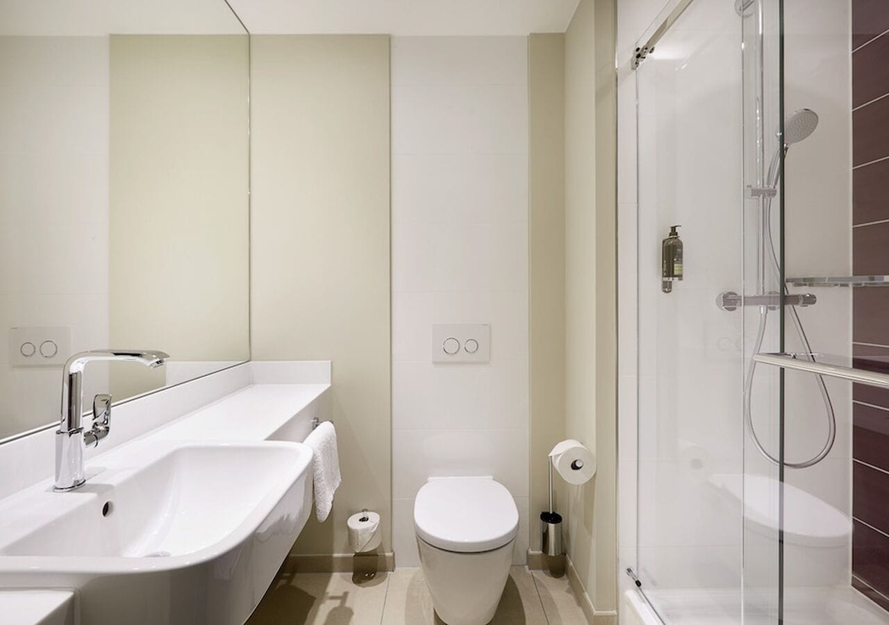 Ein modernes Badezimmer mit Waschbecken, Toilette und Dusche – alles in Weiß.