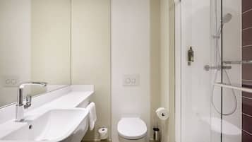 Ein modernes Badezimmer mit Waschbecken, Toilette und Dusche – alles in Weiß.
