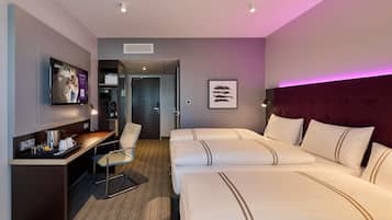 Ein Hotelzimmer mit einem Bett, einem Schreibtisch, einem Stuhl, einer Kaffeemaschine und einem gerahmten Bild an der Wand.