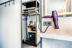 A compact room with a built-in wardrobe, a hairdryer on a wooden shelf, and a small desk area. - Premier Inn Konstanz (Konstanz)
