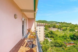 A balcony with a table and chairs, overlooking a green landscape with buildings. - [Casa Azzurra] Terrace/Seaview (Lerici)