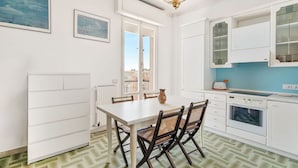A kitchen with white cabinets, a dining table, and chairs. - [Casa Azzurra] Terrace/Seaview (Lerici)