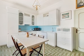 A kitchen with white cabinets, a dining table, and chairs. - [Casa Azzurra] Terrace/Seaview (Lerici)