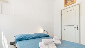 A room with a bed, a blue pillow, and neatly folded white towels. - [Casa Azzurra] Terrace/Seaview (Lerici)