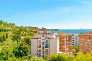 A coastal residential area with multi-story buildings, a clear sky, and a view of the sea. - [Casa Azzurra] Terrace/Seaview (Lerici)