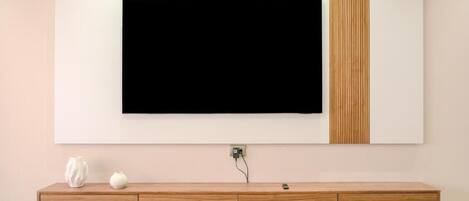 Een moderne woonkamer met een wandtelevisie, een houten console en een wandplank.