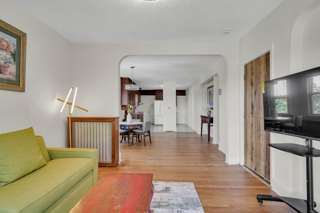Een woonkamer met een bank, een salontafel, een televisie en een eethoek met stoelen en een tafel.
