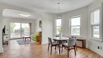 A spacious living room with a round dining table, a green sofa, and a chandelier.