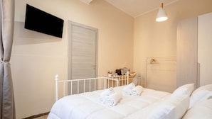 A bedroom with a bed, a TV mounted on the wall, a bedside table with a lamp, and a wardrobe. - ALL Covi del Viaggiatore – Elegant 2-Bedroom Stay in Bari (Bari)