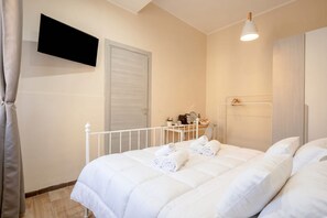 A bedroom with a bed, a TV mounted on the wall, a bedside table with a lamp, and a wardrobe. - ALL Covi del Viaggiatore – Elegant 2-Bedroom Stay in Bari (Bari)