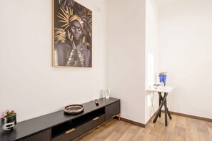A modern interior with a dark console table, a white side table with a vase, and a framed artwork on the wall. - ALL Covi del Viaggiatore – Elegant 2-Bedroom Stay in Bari (Bari)