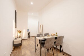 A dining area with a table set for four, a vase with flowers, and a mirror on the wall. - ALL Covi del Viaggiatore – Elegant 2-Bedroom Stay in Bari (Bari)